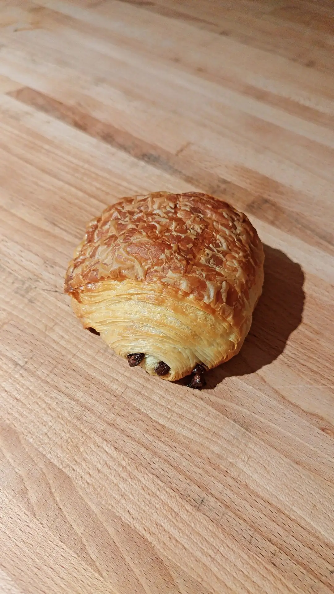 Krokant vegan pain au chocolat van Nona's Bakery met drie staafjes chocolade